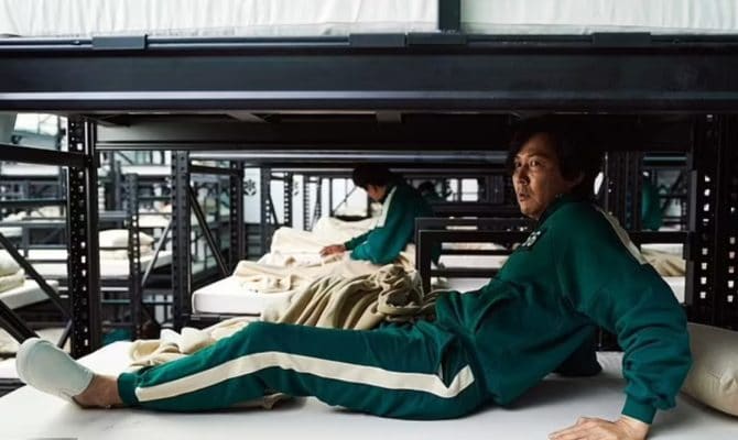 Seong Gi-hun بطل العرض يرتدي بدلة باللون الفيروزي وحذاء سهل الارتداء في العرض