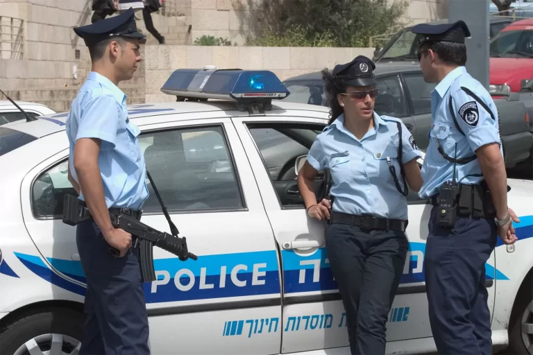 3 عناصر من الشرطة الإسرائيلية يقفون إلى جانب سياة شرطة